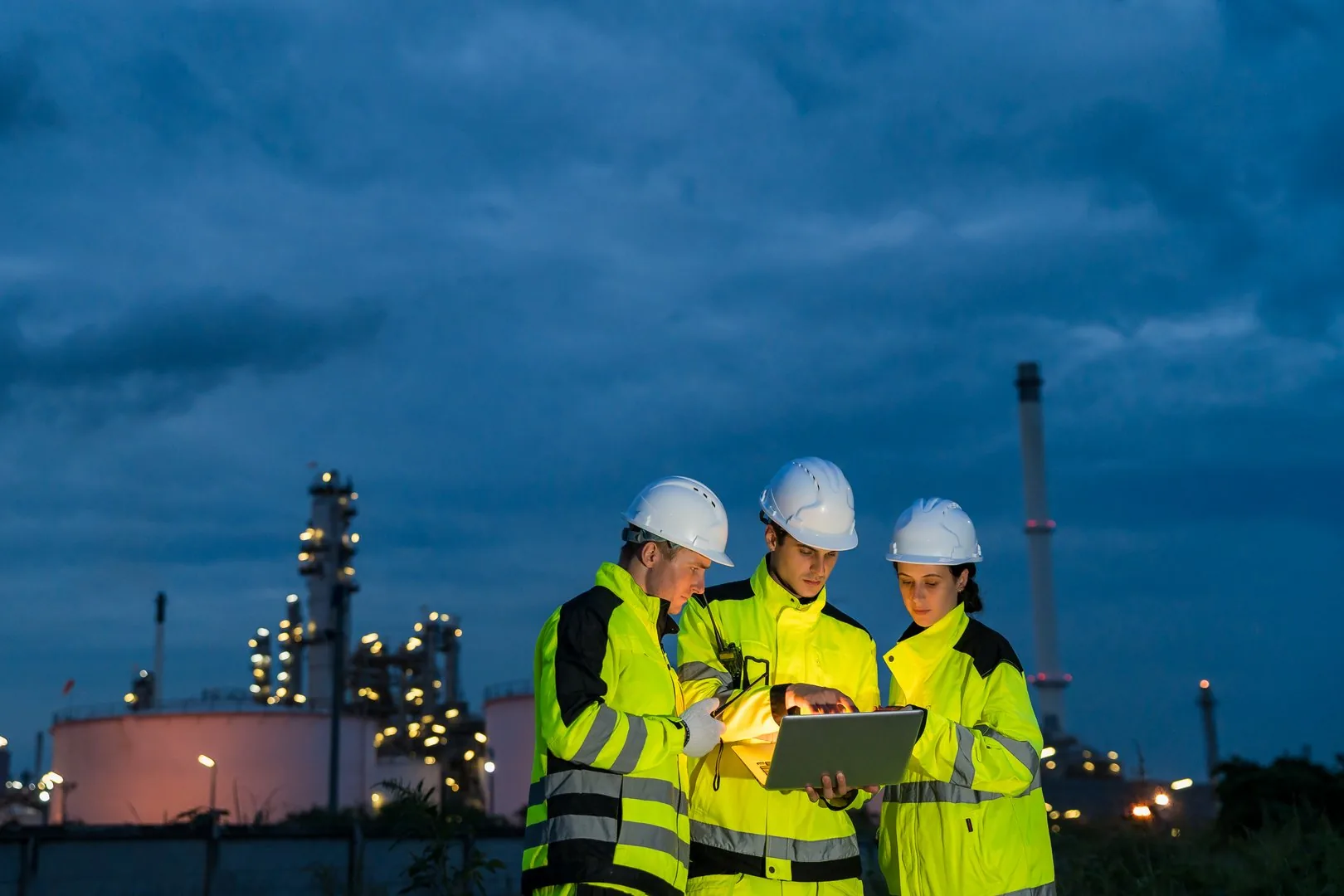 Engineering team working with a laptop during a night shift at a petrochemical refinery