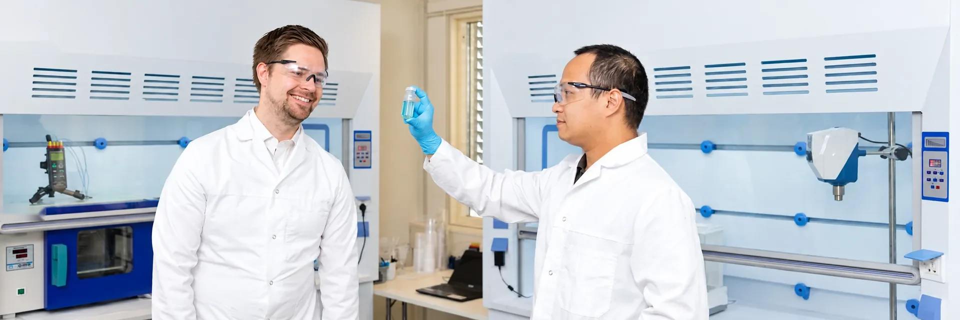 Two laboratory technicians examining a fluid sample in a well chemistry laboratory